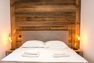A bedroom with a wooden wall and a bed
