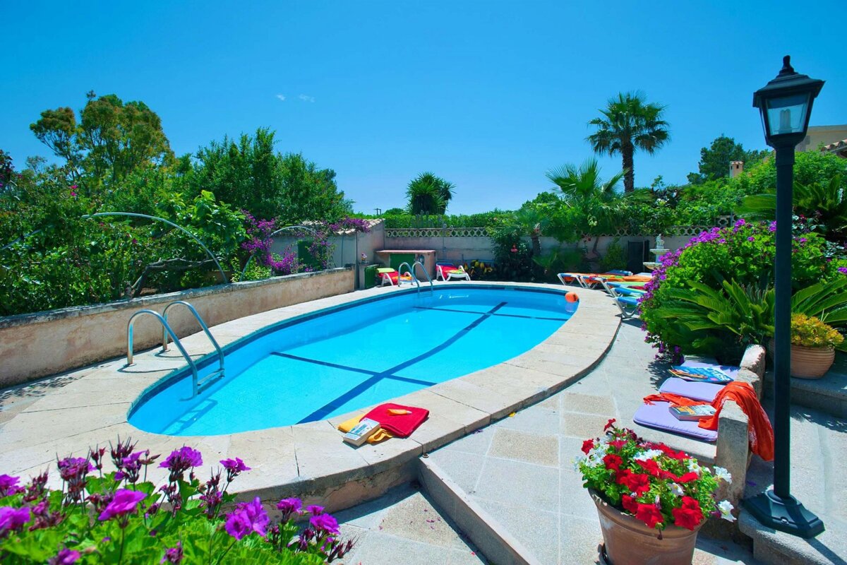 A swimming pool surrounded by flowers and a lamp post