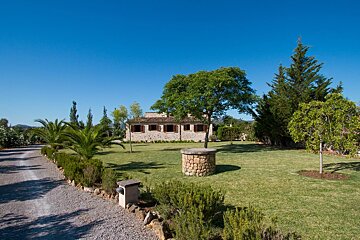 A stone house sits in the middle of a lush green field