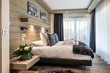 A bedroom with a bed and a nightstand with a vase of flowers on it