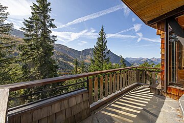 A balcony with a view of mountains and trees