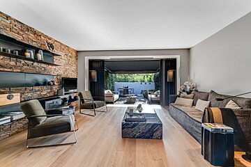Modern living room featuring a stone accent wall, stylish furniture, and large glass doors opening to an outdoor patio.