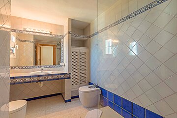 A bathroom with blue and white tiles and a toilet