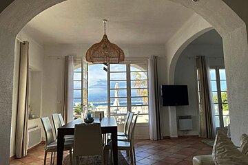 A dining room with a table and chairs and a television