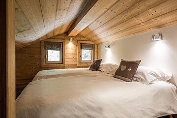 A bedroom with two beds and a wooden ceiling