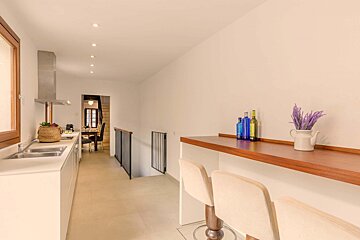 A kitchen with a sink and a shelf with bottles on it