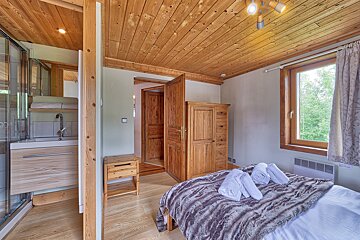 A bedroom with a wooden ceiling and a bed