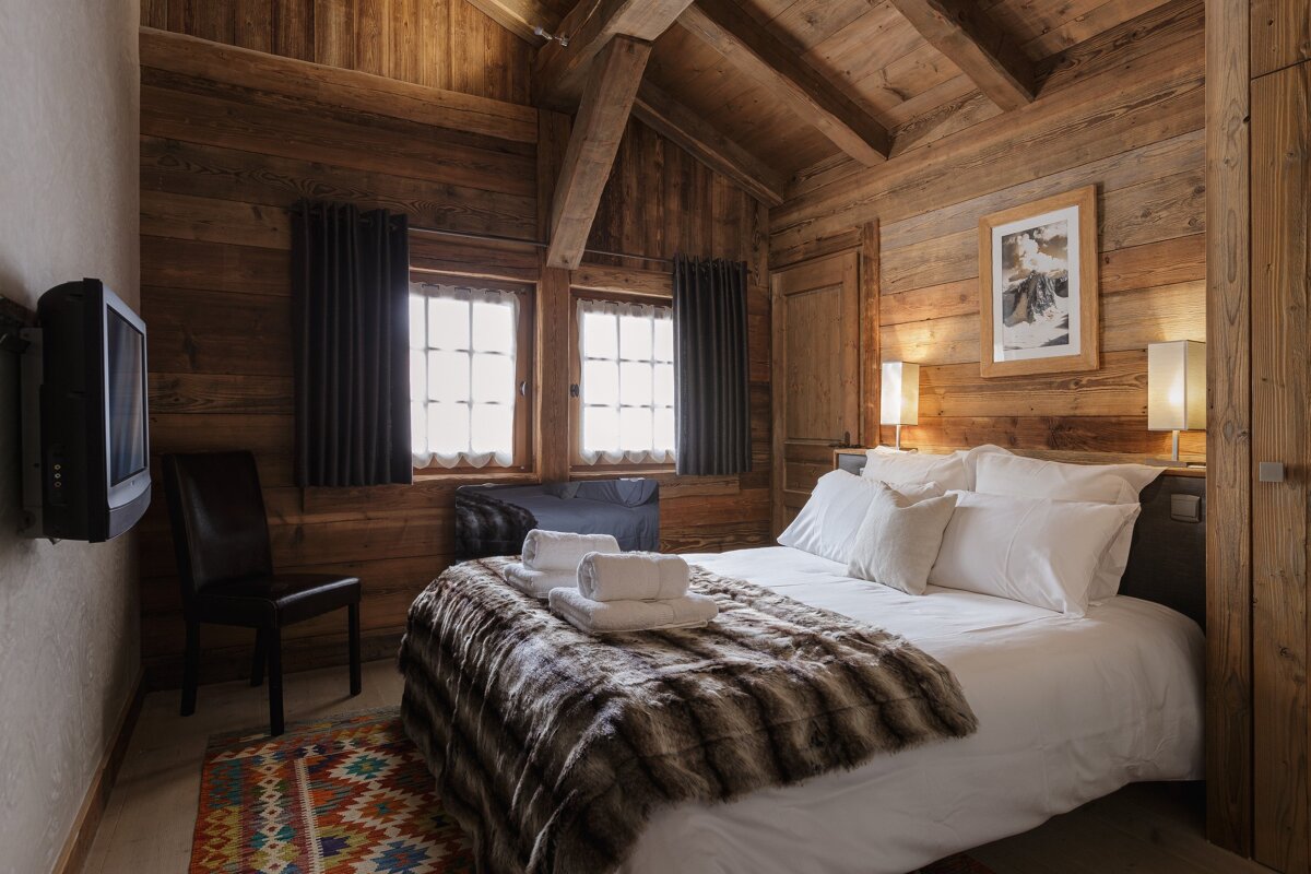A bedroom with a bed and a television on the wall