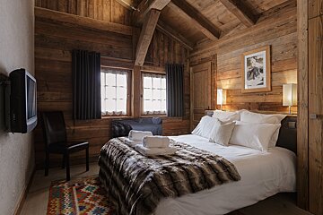 A bedroom with a bed and a television on the wall