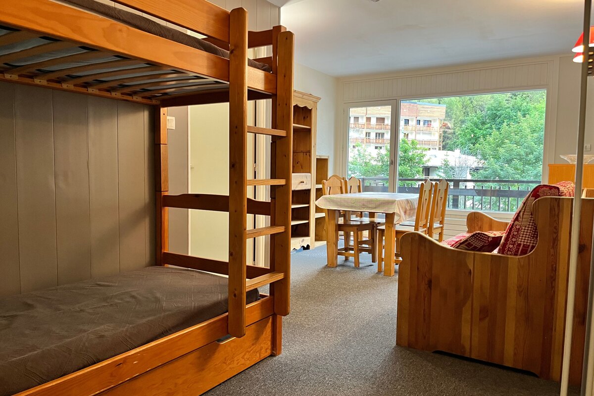 A bunk bed in a room with a table and chairs