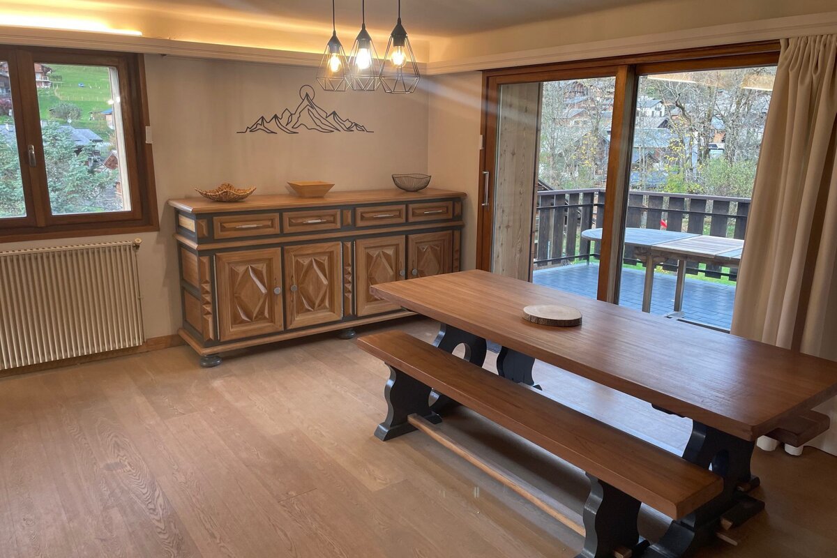A dining room with a table and benches and a sliding glass door