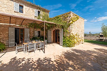 A patio with a table and chairs in front of a stone building
