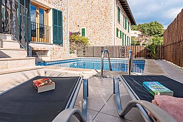 A book titled apples to apples sits on a lounge chair next to a pool