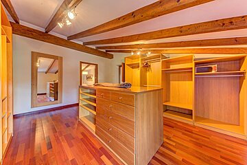 A walk in closet with wooden shelves and drawers