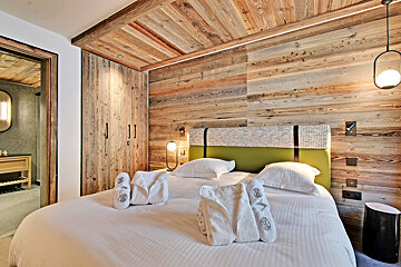 A bed in a hotel room with a green headboard