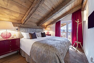 A bedroom with a bed and a window with a ski lift in the background