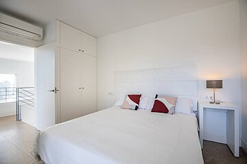 A bedroom with a white bed and a lamp
