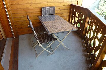 A table and chairs on a balcony with a wooden railing