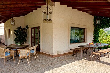 A patio with a table and chairs under a roof