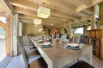 A dining room table with a bottle of wine on it