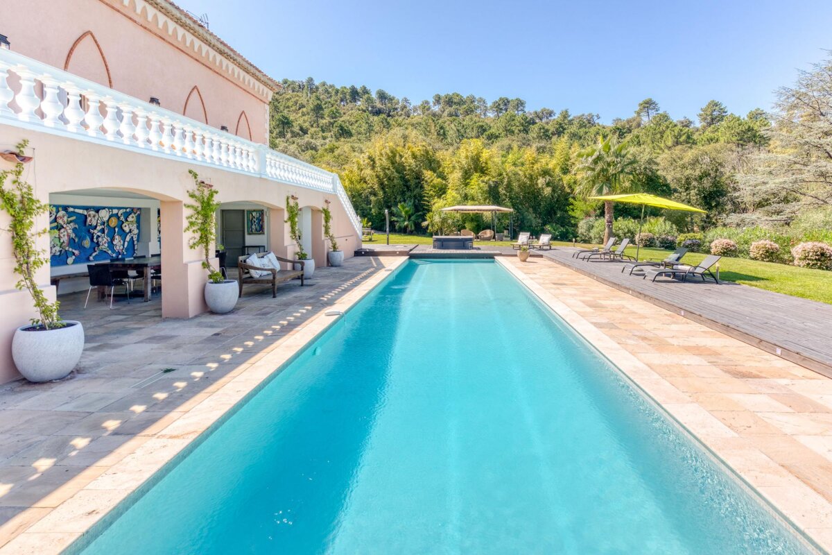 A large swimming pool is surrounded by chairs and umbrellas