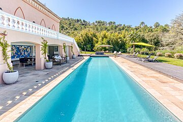 A large swimming pool is surrounded by chairs and umbrellas