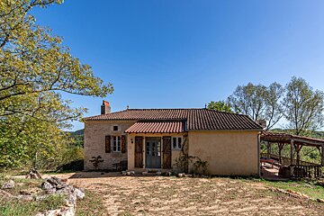 A small house with a red tile roof and shutters