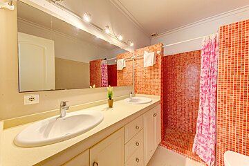 A bathroom with two sinks and a pink shower curtain