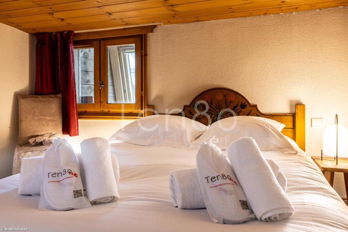 A bed with white sheets and towels that say ten80 on them