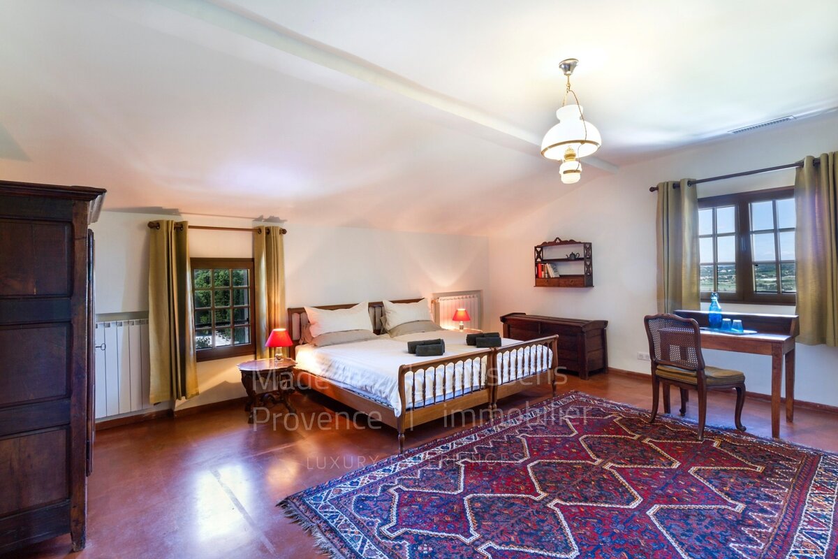 A bedroom with two beds and a rug that says made provence