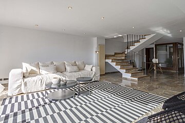 A living room with a couch and stairs in the background