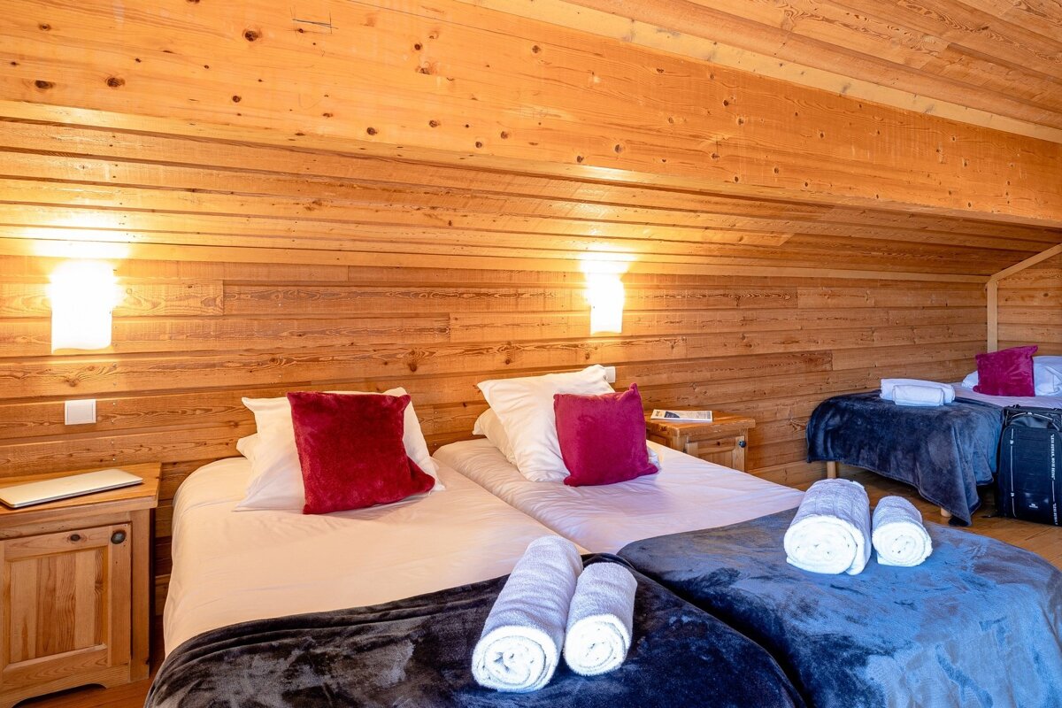 A bedroom with three beds and a laptop on a nightstand