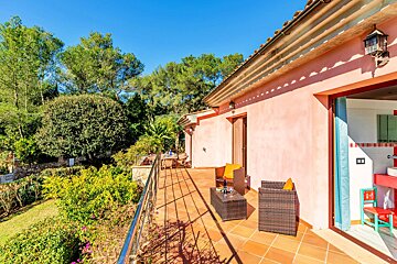 A pink house has a balcony with a table and chairs