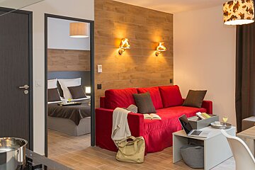 A living room with a red couch and a laptop on a table