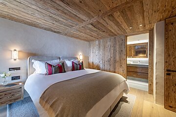 A bedroom with a large bed and wooden walls