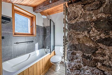 A bathroom with a bathtub toilet and window