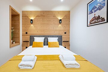 A bedroom with a mont blanc poster on the wall above the bed