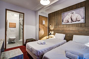 A bedroom with two beds and a picture of polar bears on the wall