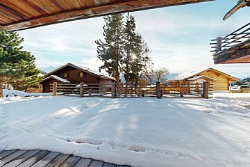 A snowy area with a fence and a house in the background