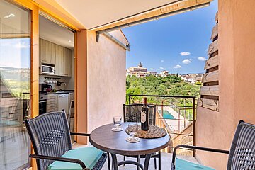 A balcony with a table and chairs and a bottle of wine