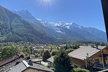 A view of a mountain range with a few houses in the foreground