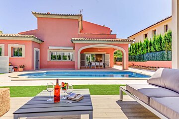 A bottle of wine sits on a table in front of a pink house