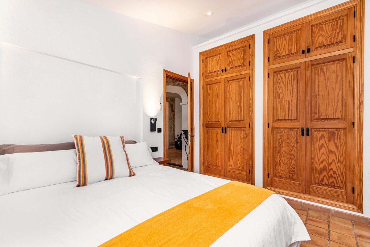 A bedroom with a bed and closets with wooden doors