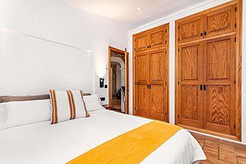 A bedroom with a bed and closets with wooden doors