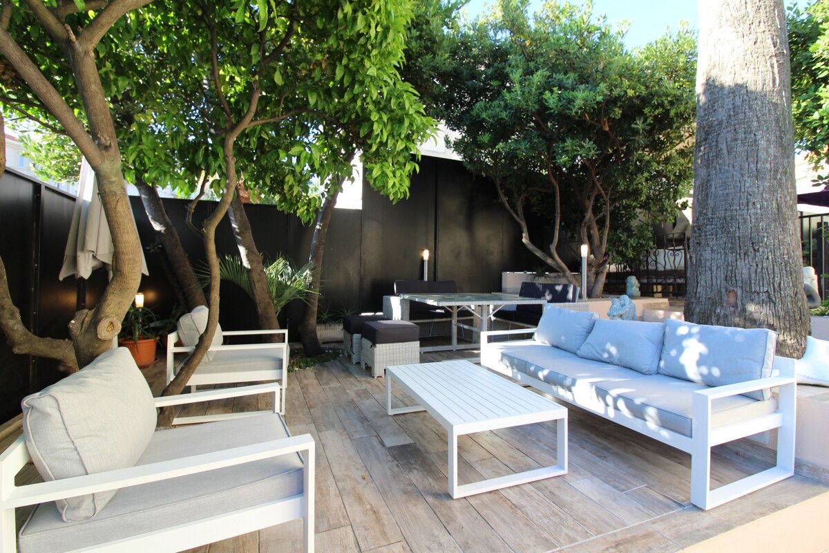 A patio with a couch and chairs under a tree