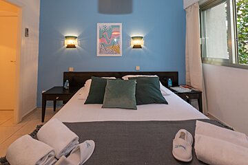 A bedroom with a blue wall and a picture of a flamingo above the bed