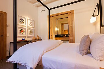 A bedroom with a canopy bed and a bathroom