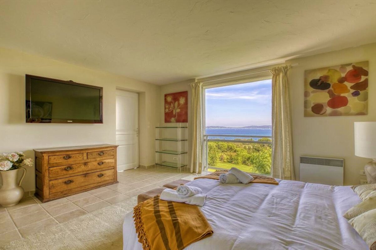 A bedroom with a large flat screen tv on the wall above the bed