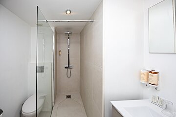 A bathroom with a walk in shower and two bottles of soap on the wall