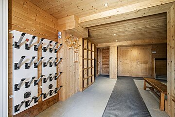 Rustic wood-paneled ski room featuring wall-mounted boot dryers, storage cubbies, and a bench.